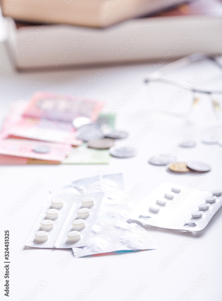 Fototapeta premium Medicine, finance, health care and drug trafficking - medical pills or drugs and coin on white background.