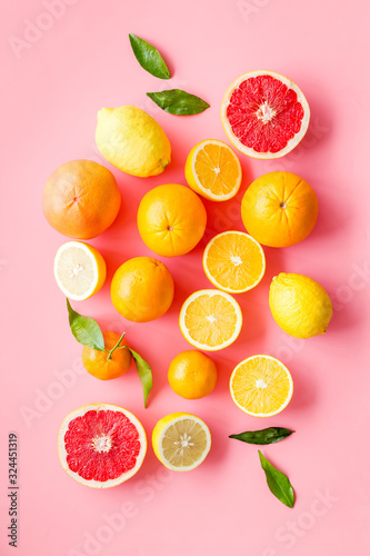 Fresh citrus background. Oranges  grapefruits  leaves - whole fruits and halfs - on pink background top-down