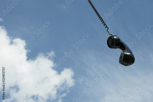 vintage black phone with line hanging from the sky. Conceptual photography talking to someone from above