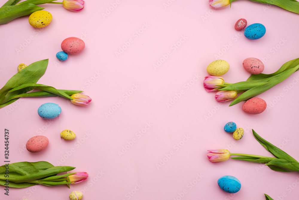 Beautiful pink tulips and colored Easter eggs on a pink background.