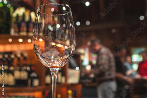 Empty wine glass with blurry background of people at the bar