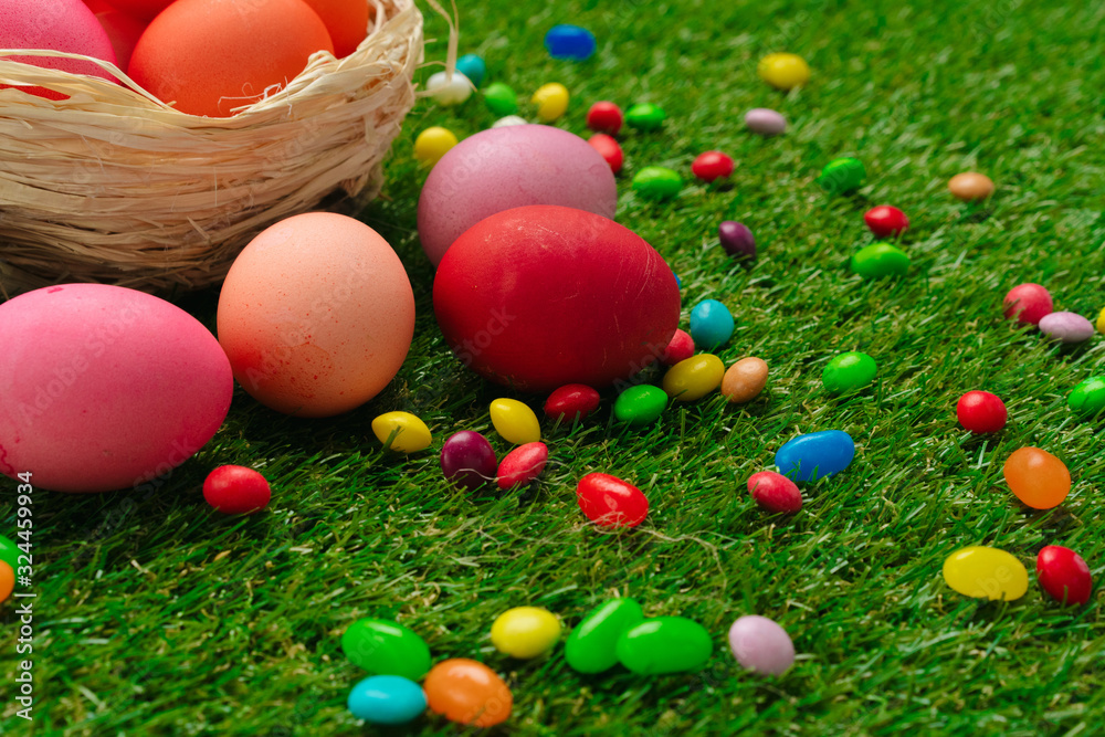 Colored eggs and vibrant candies on grass. Easter composition