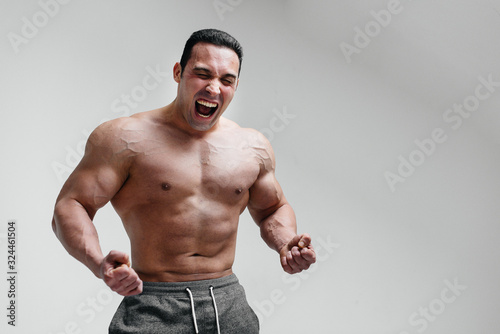 A sporty guy screams in rage against a white background. Anger. Threat