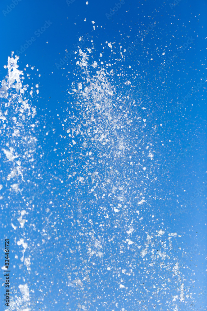 Splashing water from a fountain on a background of blue sky