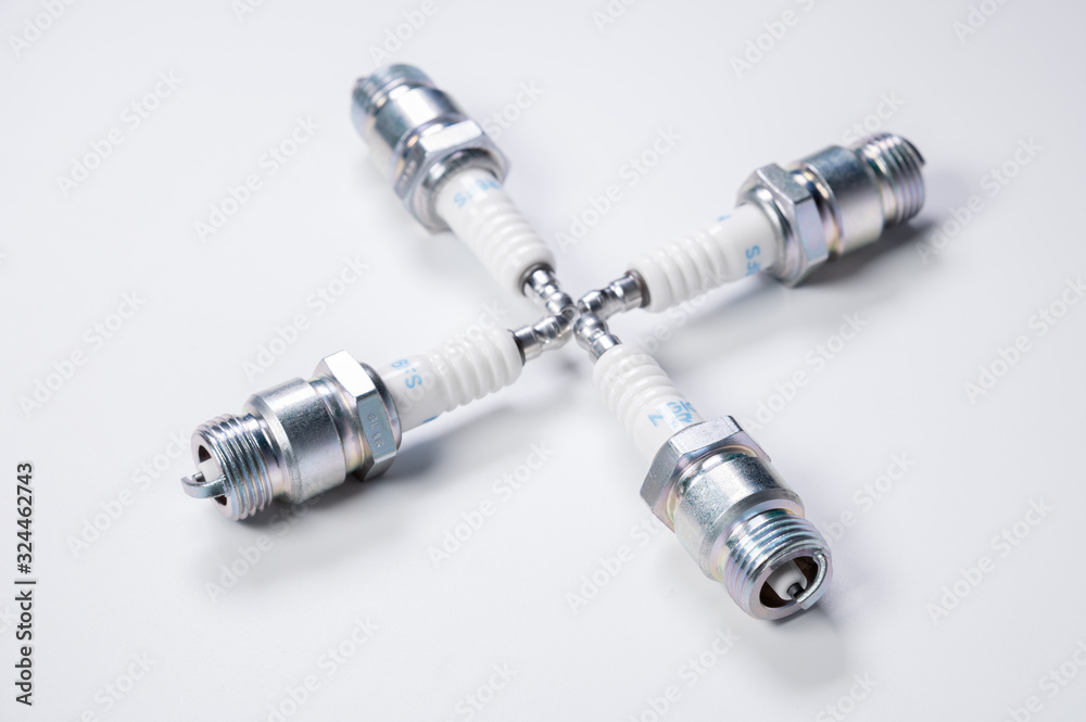 Subject shooting on a gray background. new four spark plugs, spare parts for a gasoline engine. The concept of new auto parts and maintenance Subject shooting on a gray background. new four spark plugs, spare parts for a gasoline engine. The concept of new auto parts and maintenance