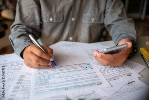Budget planning concept, Accountant is calculating company's annual tax. Calendar 2020 and personal income tax forms for those who have income under US law placed on office desk.