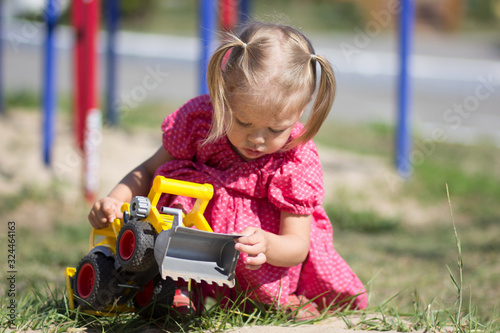 Caucasian little girl of two years old playing with toy car on playground © Tatiana Foxy