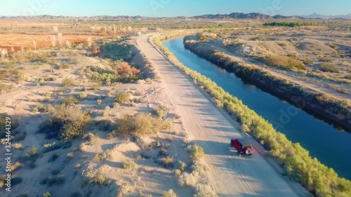 Drone aerial view following vehicle driving along the Gila Gravity Canal - Yuma Arizona