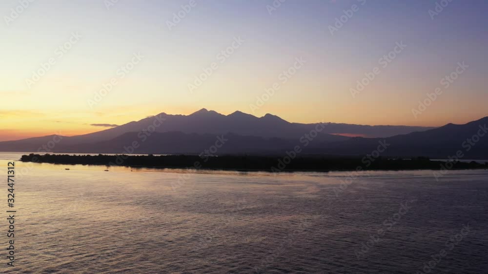 Purple sunset over the peaceful sea water with uninhabited island and small mountain range in the distance. Misty evening scenery, Seychelles. Purple sunset over the peaceful sea water with uninhabited island and small mountain range in the distance. Misty evening scenery, Seychelles.