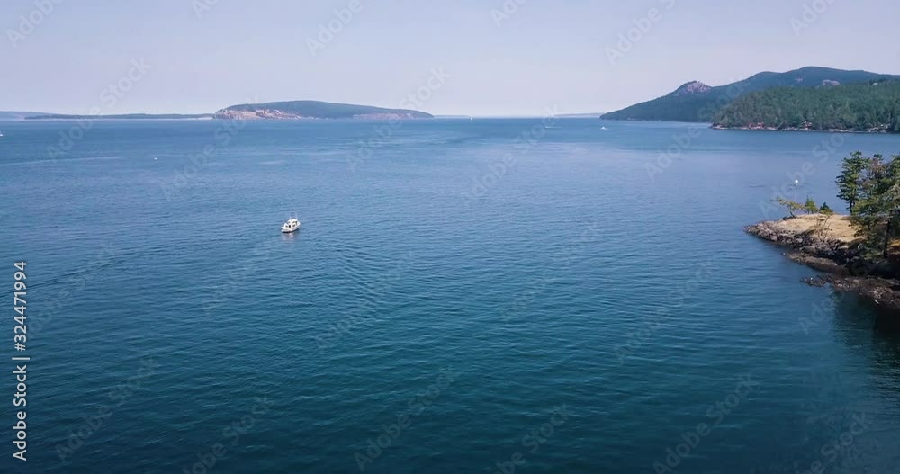 High drone over boat moving away and boats in cove at Jones Island Washington High drone over boat moving away and boats in cove at Jones Island Washington