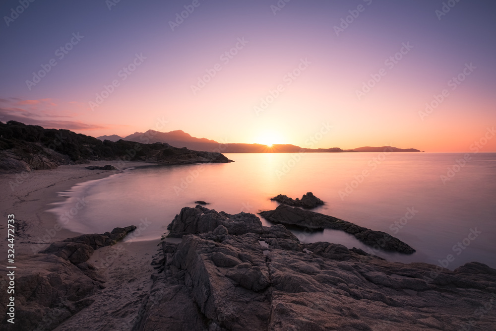 Sun setting over beach and calvi citadel in Corsica