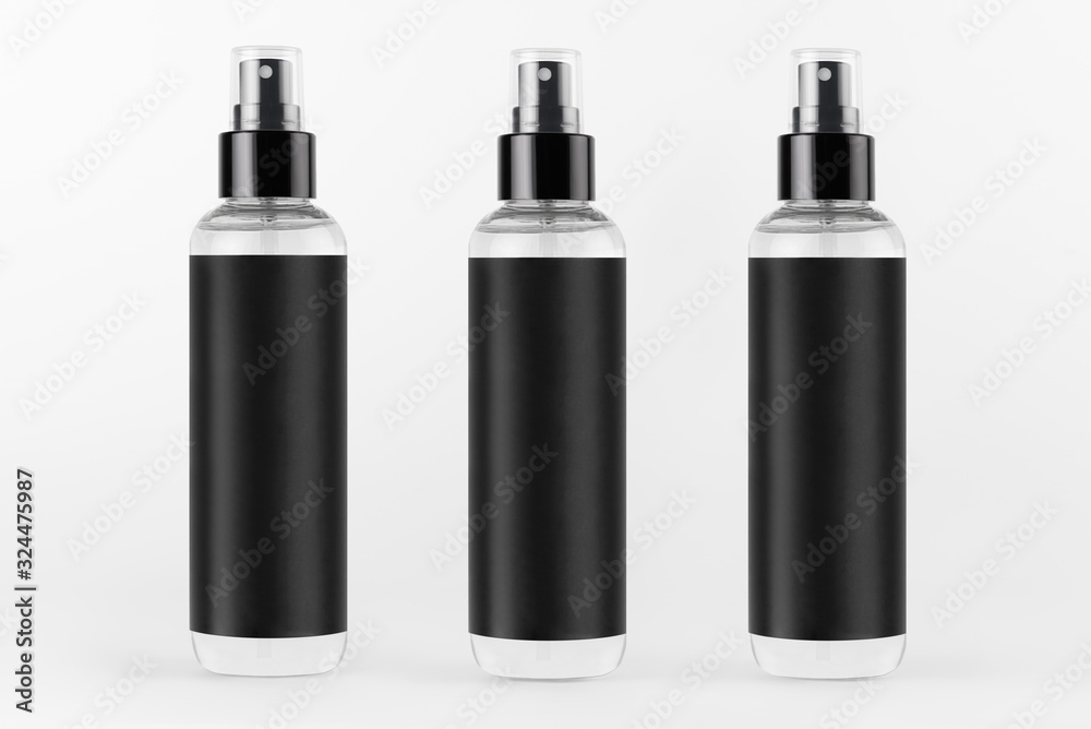Tall transparent spray dispenser bottles for cosmetics product collection with black label in a row on white background, mock up for design. Tall transparent spray dispenser bottles for cosmetics product collection with black label in a row on white background, mock up for design.