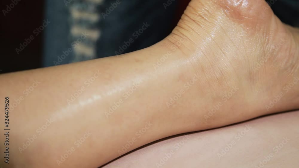 A tight shot of a man massaging the ankles of a woman A tight shot of a man massaging the ankles of a woman