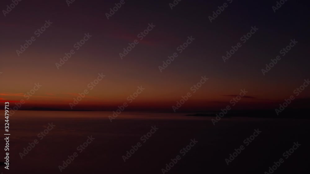Aerial pan shot of silhouette of archipelago in front of a dark red sunset backdrop. Aerial pan shot of silhouette of archipelago in front of a dark red sunset backdrop.