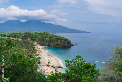 Beautiful landscape with a view of the lost beach in Bali. Virgin beach with white sand and white traditional fishing boats. The view from the top. Blue sky with clouds
