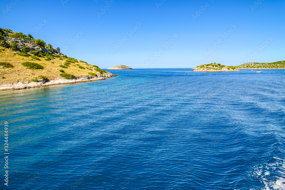 Adriatic coast with rocky beach, small islands, boats and sailing yachts in the blue sea, Croatia, Dalmatia