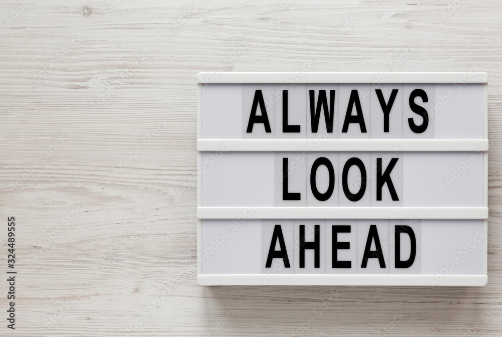'Always look ahead' words on a lightbox on a white wooden surface, top view. Overhead, from above, flat lay. Copy space. 'Always look ahead' words on a lightbox on a white wooden surface, top view. Overhead, from above, flat lay. Copy space.