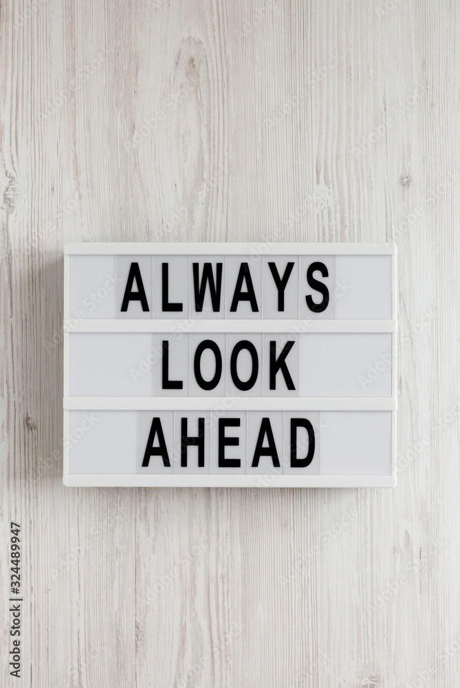 'Always look ahead' words on a lightbox on a white wooden surface, top view. Overhead, from above, flat lay. 'Always look ahead' words on a lightbox on a white wooden surface, top view. Overhead, from above, flat lay.