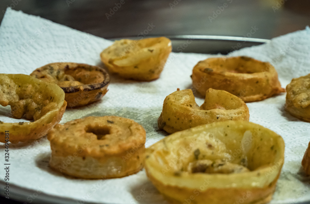 Close up of deep fried onion rings laid out onto a paper kitchen towel to dry before eating. 