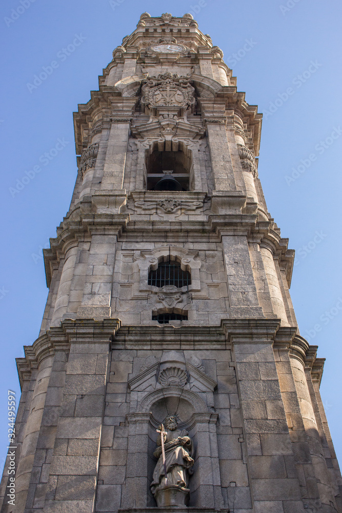 Clerigos Tower in Porto bottom view. Famous tower with clock and bell in Porto. Religious architecture concept. Exterior of ancient temple. Catholic tower on clear blue sky. Clerigos Tower in Porto bottom view. Famous tower with clock and bell in Porto. Religious architecture concept. Exterior of ancient temple. Catholic tower on clear blue sky.