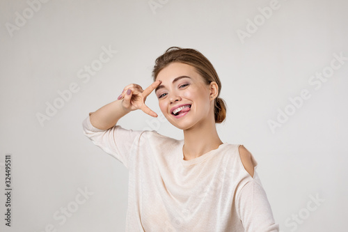 smiling young woman showing victory sign and looking at camera. Human emotions, facial expression concept.