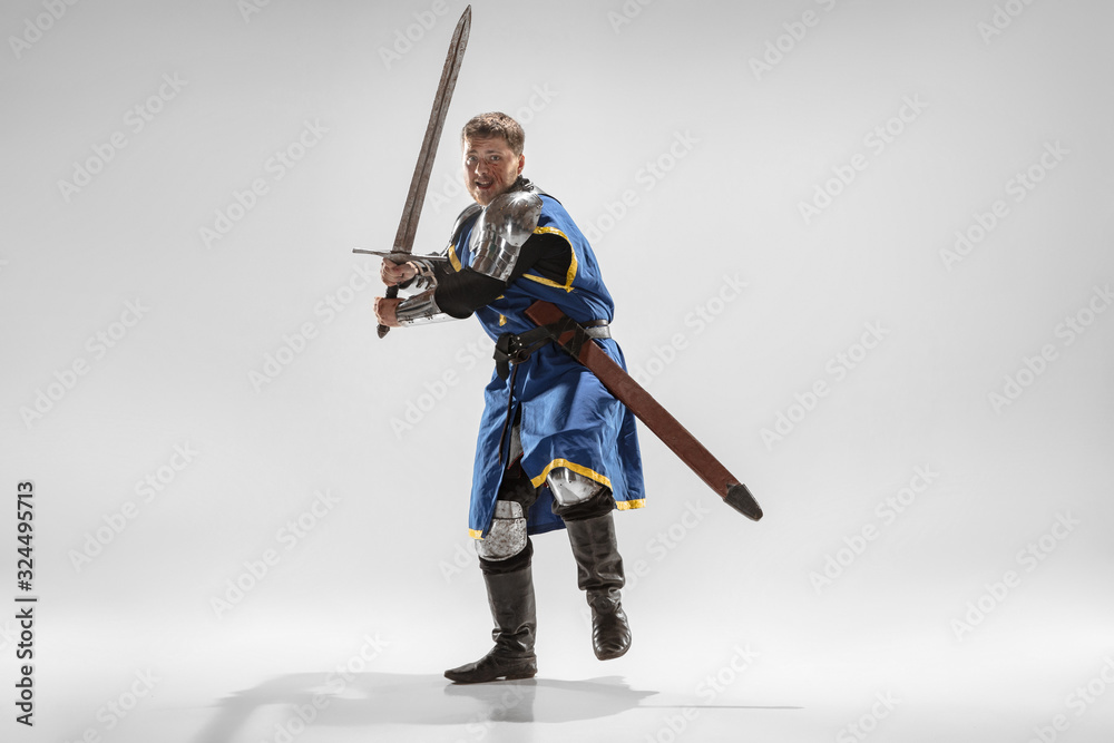 Brave armored knight with professional weapon fighting isolated on white studio background. Historical reconstruction of native fight of warriors. Concept of history, hobby, antique military art. Brave armored knight with professional weapon fighting isolated on white studio background. Historical reconstruction of native fight of warriors. Concept of history, hobby, antique military art.