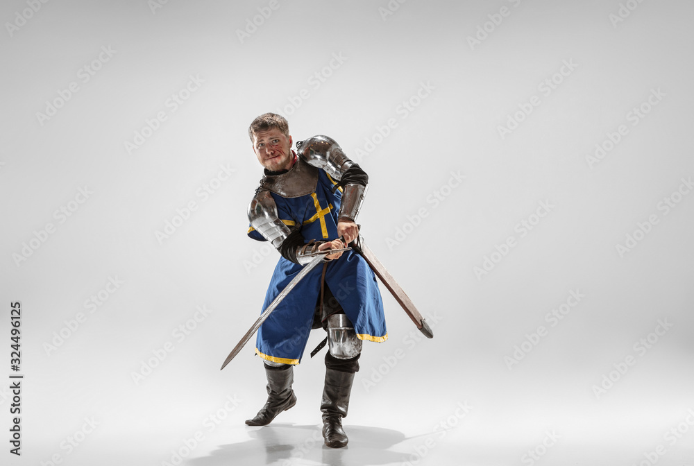 Brave armored knight with professional weapon fighting isolated on white studio background. Historical reconstruction of native fight of warriors. Concept of history, hobby, antique military art. Brave armored knight with professional weapon fighting isolated on white studio background. Historical reconstruction of native fight of warriors. Concept of history, hobby, antique military art.