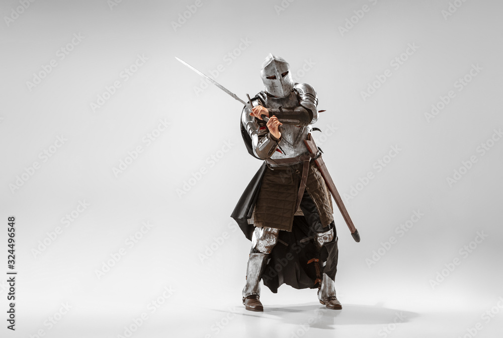 Brave armored knight with professional weapon fighting isolated on white studio background. Historical reconstruction of native fight of warriors. Concept of history, hobby, antique military art. Brave armored knight with professional weapon fighting isolated on white studio background. Historical reconstruction of native fight of warriors. Concept of history, hobby, antique military art.