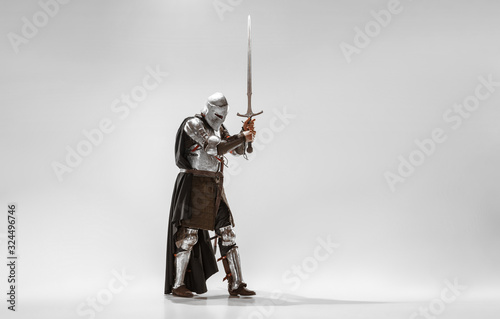 Brave armored knight with professional weapon fighting isolated on white studio background. Historical reconstruction of native fight of warriors. Concept of history, hobby, antique military art.