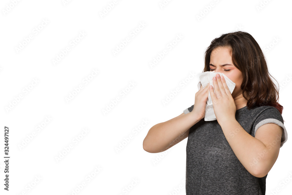 A young girl with a handkerchief sneezes. Flu and cold or allergy, on a white background A young girl with a handkerchief sneezes. Flu and cold or allergy, on a white background
