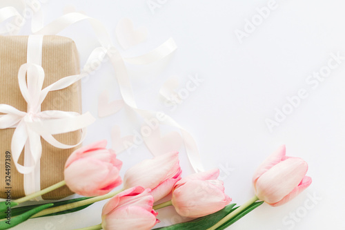 Fototapeta Naklejka Na Ścianę i Meble -  Happy Mothers day. Pink tulips and gift box with ribbon on white background, flat lay. Stylish tender image. Happy womens day. Greeting card with space for text.