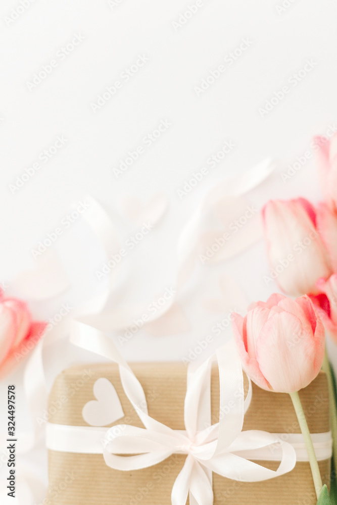 Pink tulips with ribbon and gift box on white background, flat lay. Stylish vertical image. Happy womens day. Greeting card with space for text. Happy Mothers day. Wedding or valentine mockup