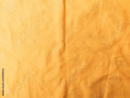 close-up fabric background of a light brown cotton fabric with wrinkles.