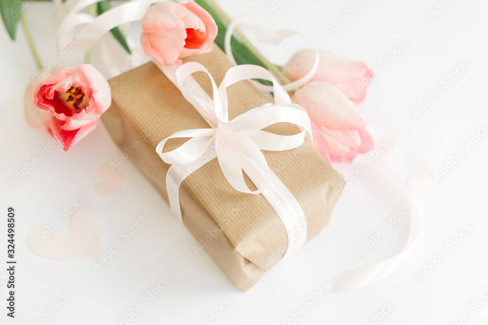 Pink tulips with ribbon and gift box on white background. Stylish soft image of spring flowers. Happy womens day. Greeting card mockup. Happy Mothers day. Hello spring Pink tulips with ribbon and gift box on white background. Stylish soft image of spring flowers. Happy womens day. Greeting card mockup. Happy Mothers day. Hello spring