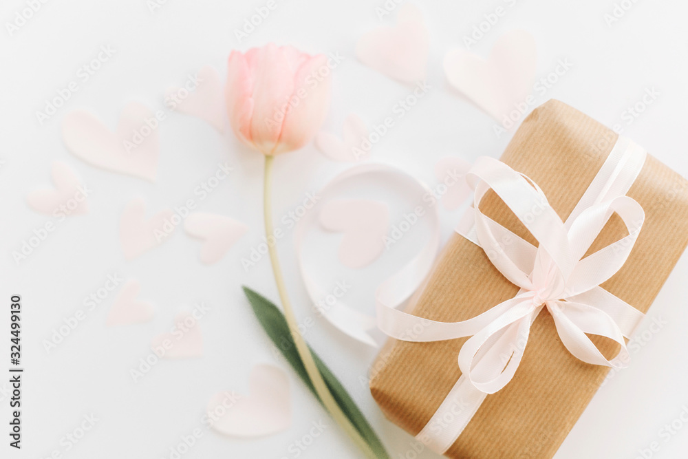 Gift box with ribbon and pink tulip flat lay on white background, space for text. Stylish soft spring image. Happy womens day. Greeting card mockup. Happy Mothers day. Romantic Valentines day