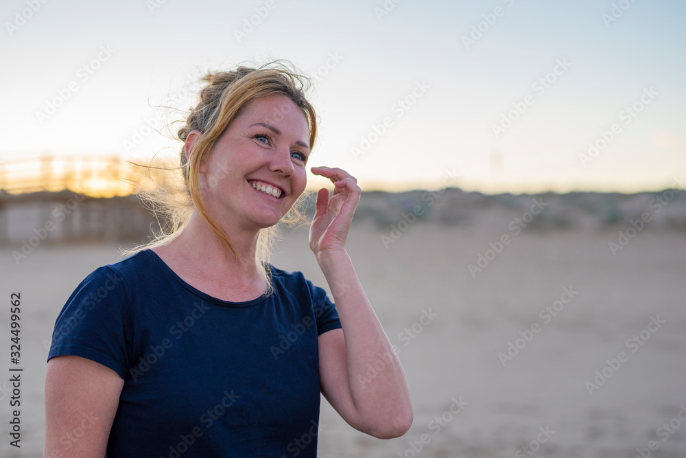 Fototapeta premium Young attractive white caucasian woman smiling and laughing on the beach warm summer evening