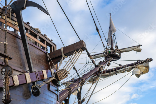 Fotografie, Obraz Anchor, masts and rigging of old pirate ship on background of cloudy blue sky