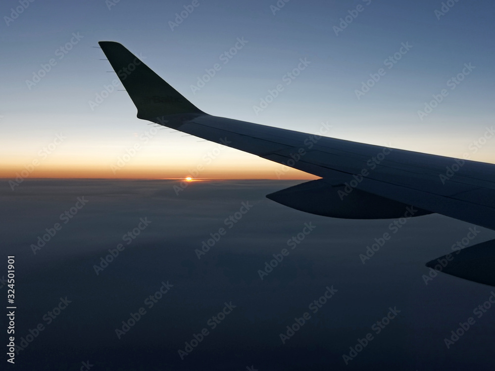 Sunset from a plain. View through the window of an aircraft. Wing of the plane above clouds Sunset from a plain. View through the window of an aircraft. Wing of the plane above clouds