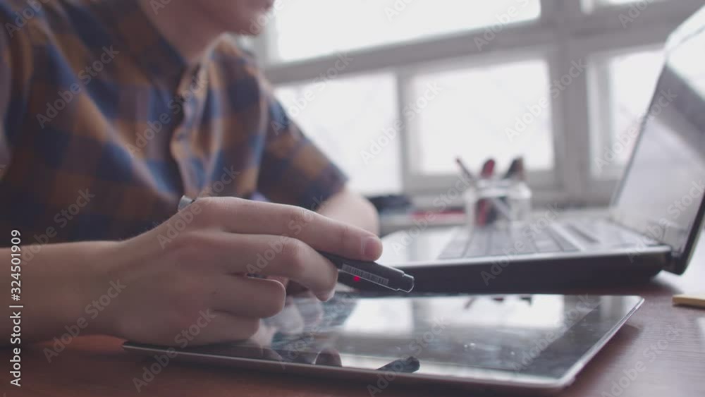 Freelancer's hand working with a stylus on a graphic tablet. Close up of the designer's hand drawing through a graphic tablet Freelancer's hand working with a stylus on a graphic tablet. Close up of the designer's hand drawing through a graphic tablet