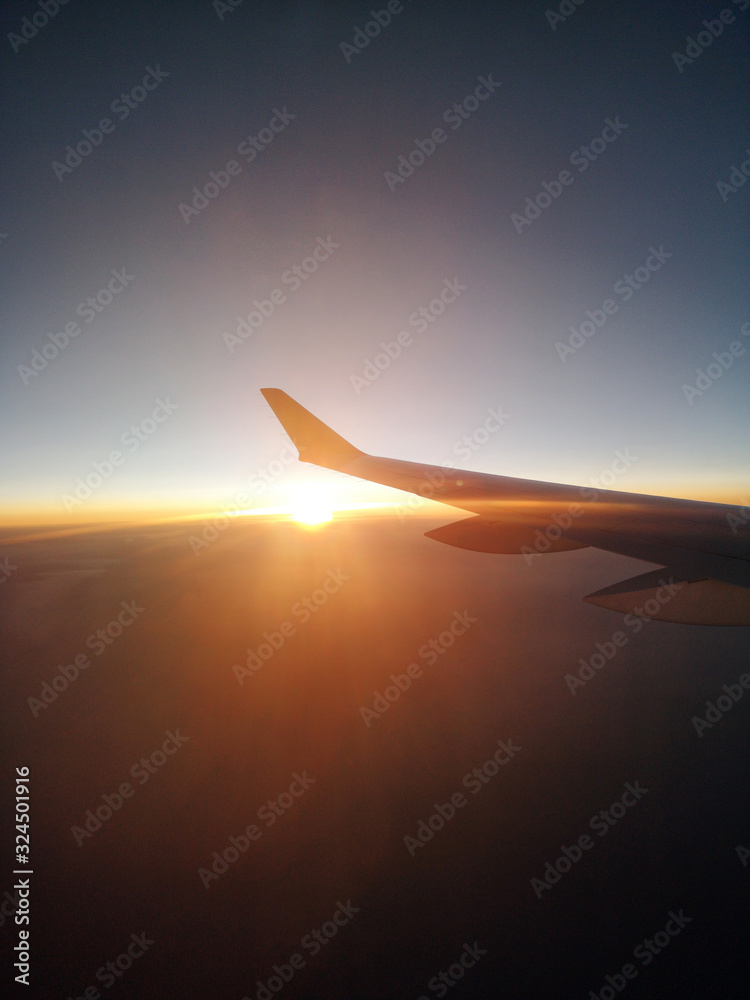 Sunset from a plain. View through the window of an aircraft. Wing of the plane above clouds Sunset from a plain. View through the window of an aircraft. Wing of the plane above clouds