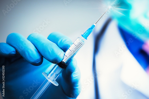 Close up hand of doctor in blue latex glove and medical gauze mask with transparent syringe. Health and vaccination concept