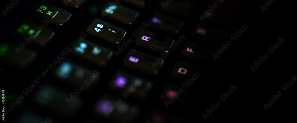 A gaming keyboard with rgb color backlight shot closeup on a black  background with space for