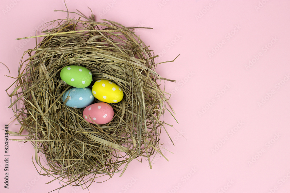 Fototapeta premium Colorful Easter egg in a nest on a pink background