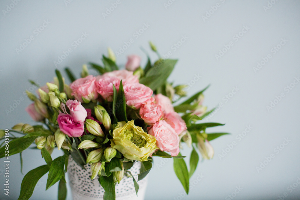 Bright bouquet with roses, eustoma and alstroemeria in white vase. Bouquet on soft blue background