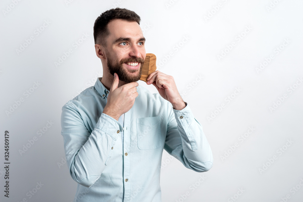 Studio shot portrait of smiling bearded man combing his beard. - Image Studio shot portrait of smiling bearded man combing his beard. - Image