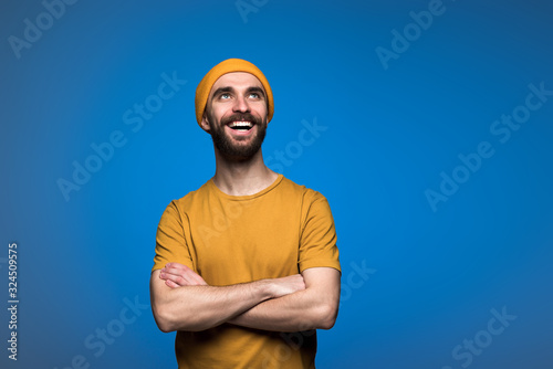 Fotografija Portrait of handsome young man folded hands and happily  looking up