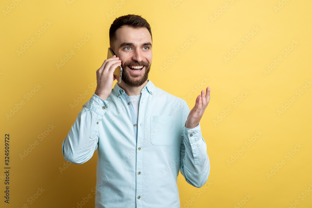 Studio portrait of young man isolated on yellow background talking on smartphone with emotion gladdness Studio portrait of young man isolated on yellow background talking on smartphone with emotion gladdness