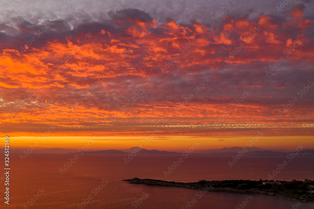Luftaufnahme eines romantischen Sonnenunterganges über dem Meer mit roten und orangenen Farbtönen