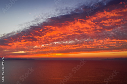 Sonnenuntergang über dem Meer mit roten und orangenen Farbtönen © moofushi