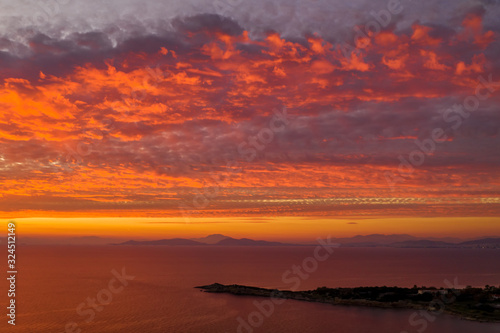 Luftaufnahme eines romantischen Sonnenunterganges über dem Meer mit roten und orangenen Farbtönen